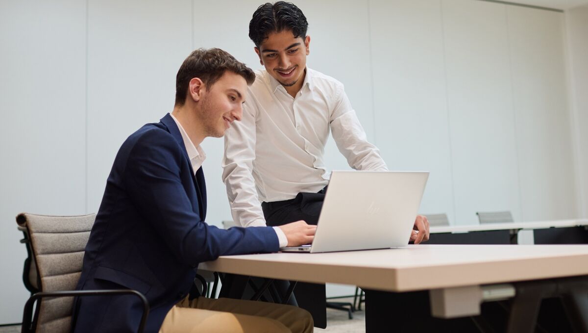 Zwei Nachwuchskräfte diskutieren über ihre Arbeit an einem Laptop