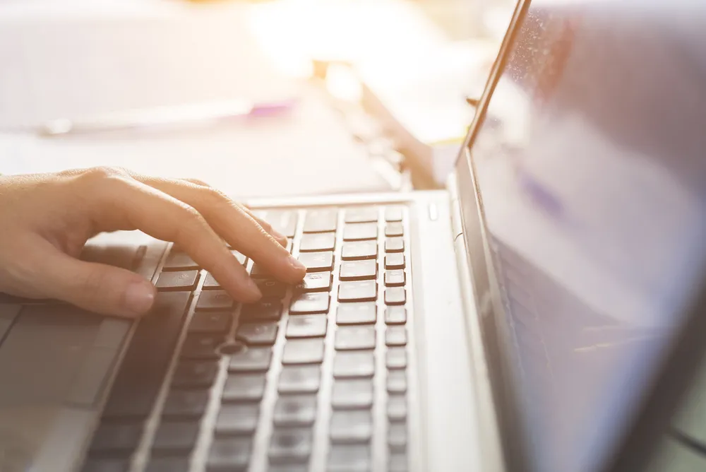 Hand auf Notebook-Tastatur Hand auf Notebook-Tastatur