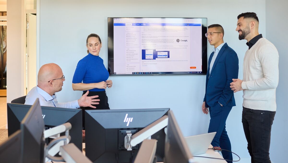 Karriere in der IT Vier Personen befinden sich in einem Konferenzraum und unterhalten sich über eine Bildschirmpräsentation.