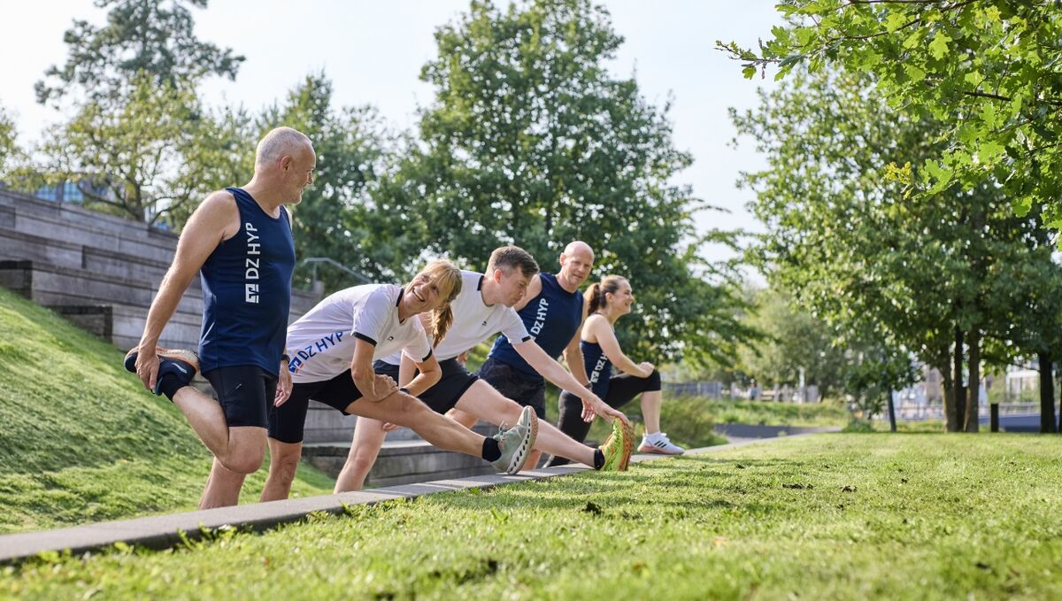 Eine Gruppe von DZ HYP Läufern dehnen sich nach einer Runde Joggen