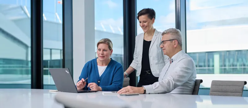 Ein Mann und eine Frau sitzen am Schreibtisch vor einem Laptop.