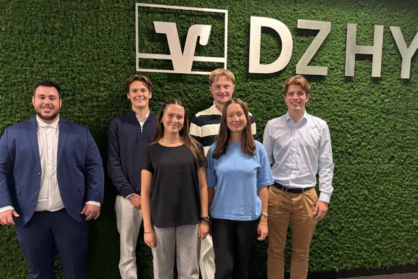 Neuer Auszubildendenjahrgang 2025 Neuer Auszubildendenjahrgang 2025 - eine Gruppe von jungen Menschen, die vor einer grünen DZ HYP Mooswand stehen.