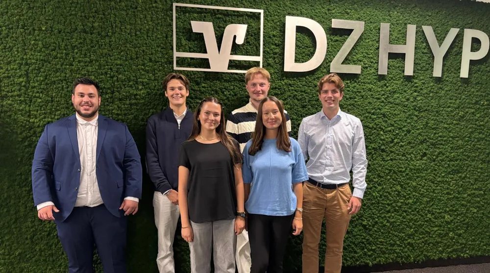 Neuer Auszubildendenjahrgang 2025 - eine Gruppe von jungen Menschen, die vor einer grünen DZ HYP Mooswand stehen.