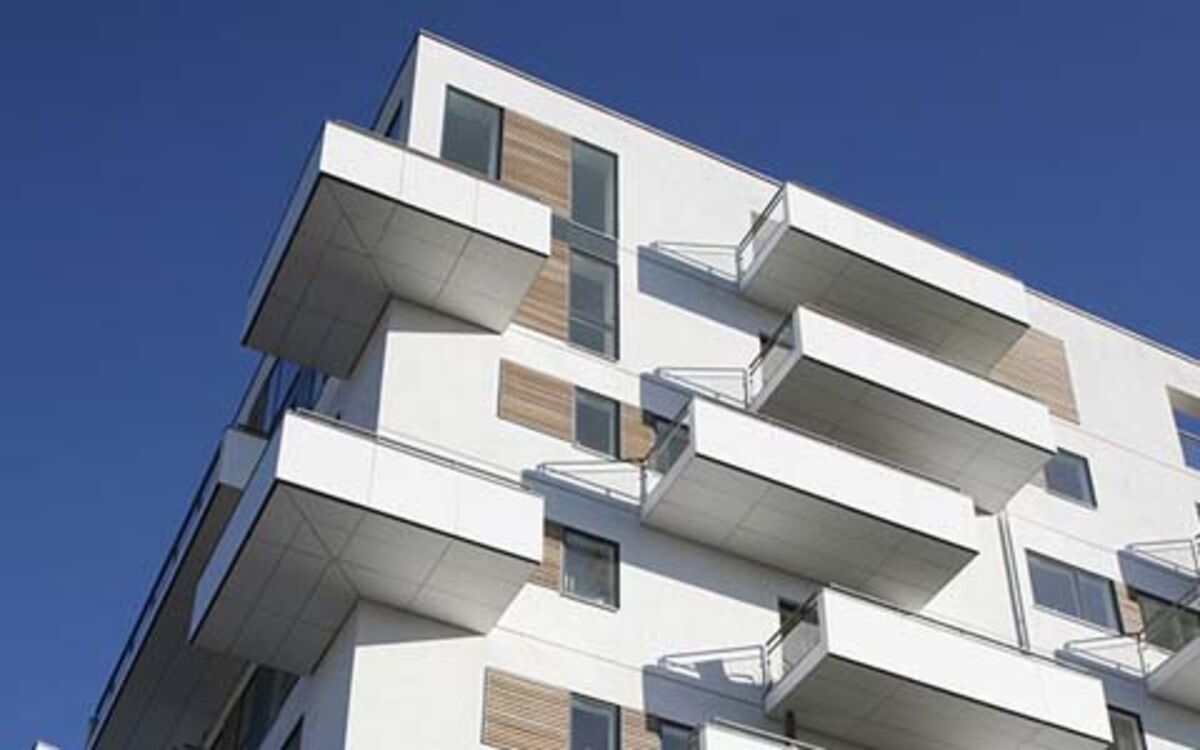 Modern, high-quality, white apartment block with large balconies in the view direction from the bottom to the top