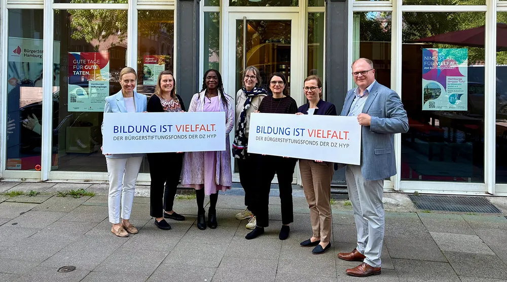 Mehrere Menschen vor einigem Gebäude mit Schildern in der Hand