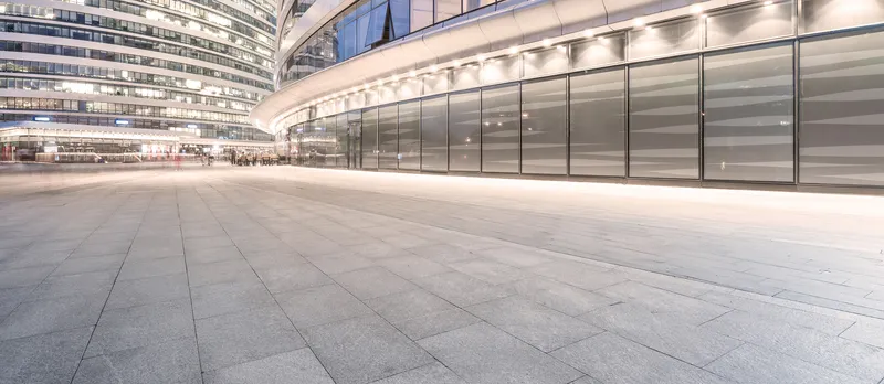 Moderne Glasfassade mit beleuchtetem Vorplatz bei Nacht