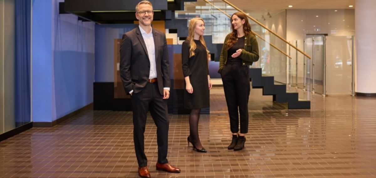 Drei Personen stehen im Foyer eines Bürogebäudes.