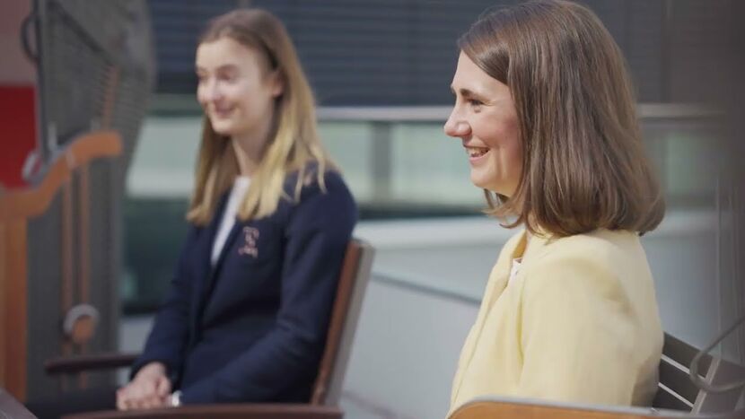 Zwei Frauen sitzen auf Stühlen und lächeln