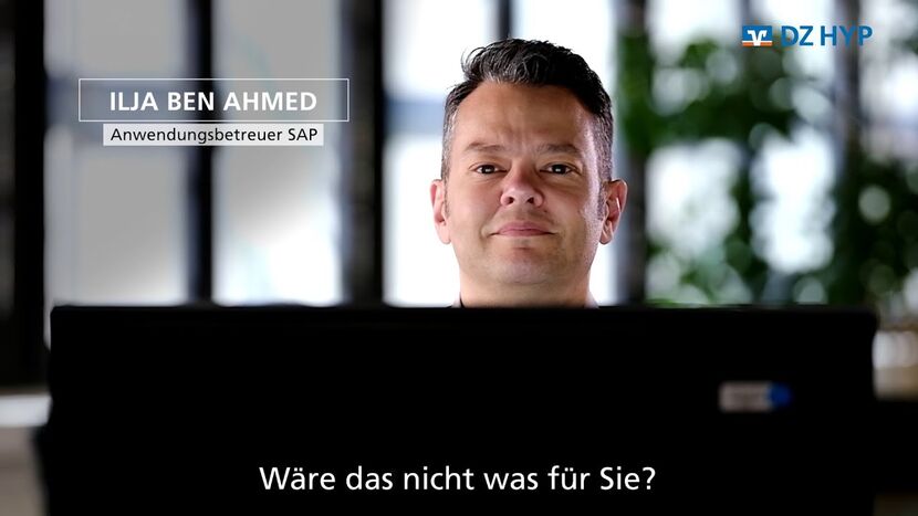 Der Anwendungsbetreuer von SAP Ilja Ben Ahmed sitzt hinter einem Bildschirm und schaut in die Kamera