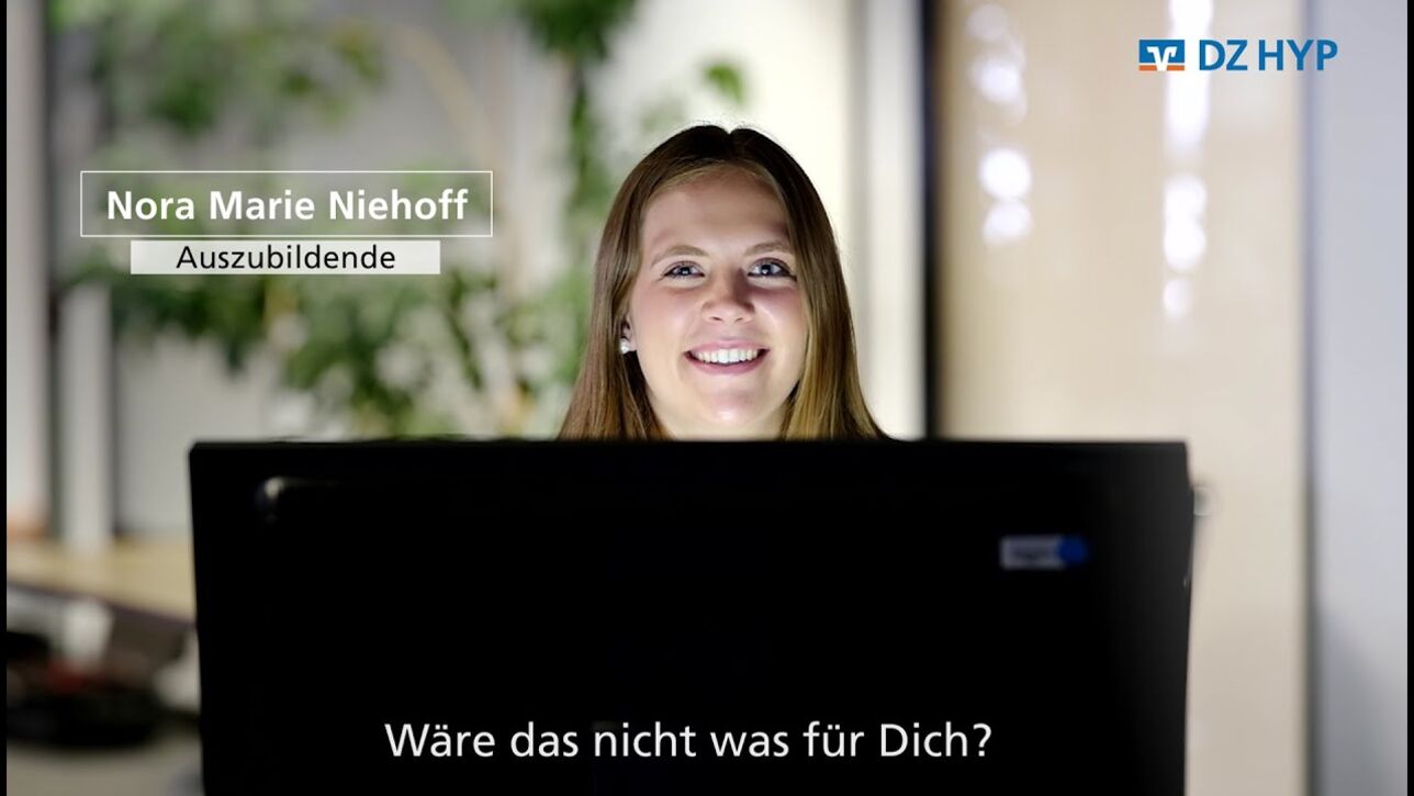 Die Auszubildende Nora Marie Niehoff sitzt hinter einem Bildschirm und schaut in die Kamera