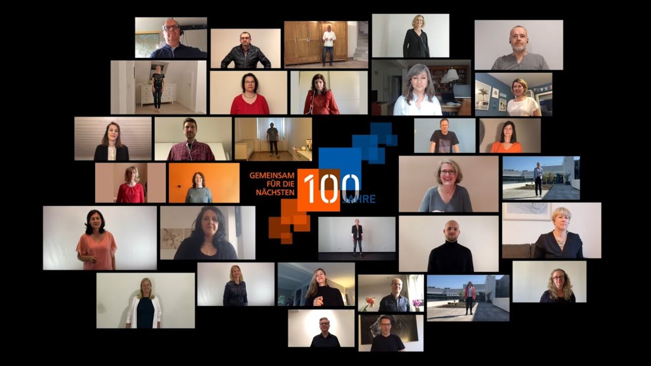 32 DZ HYP employees in a collage around a text saying "together for another 100 years"