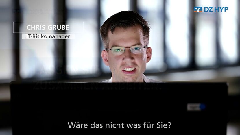 Der IT Risikomanager Chris grube sitzt hinter einem Bildschirm und schaut in die Kamera